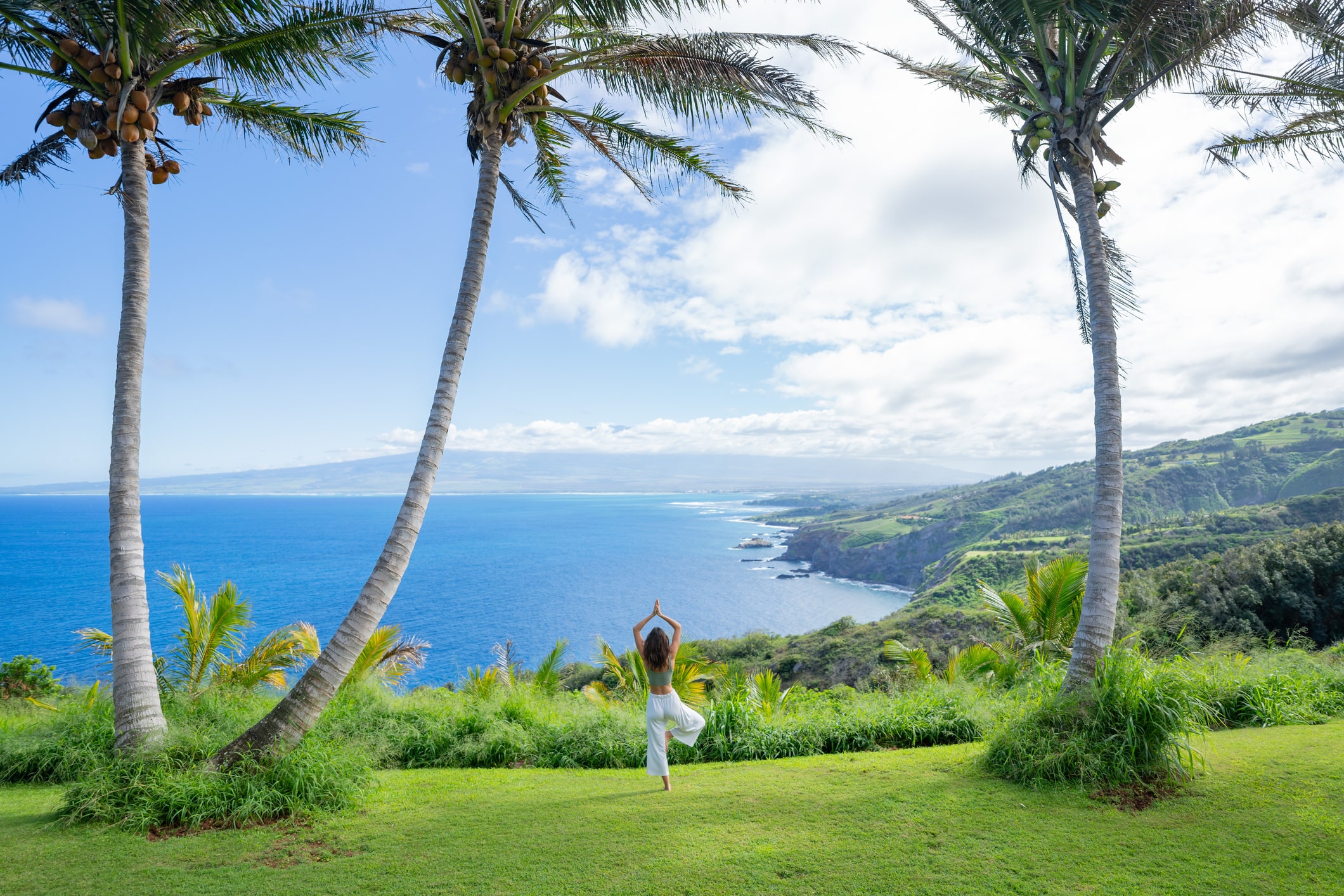 Woman does yoga at coastal overlook in Hawaii.